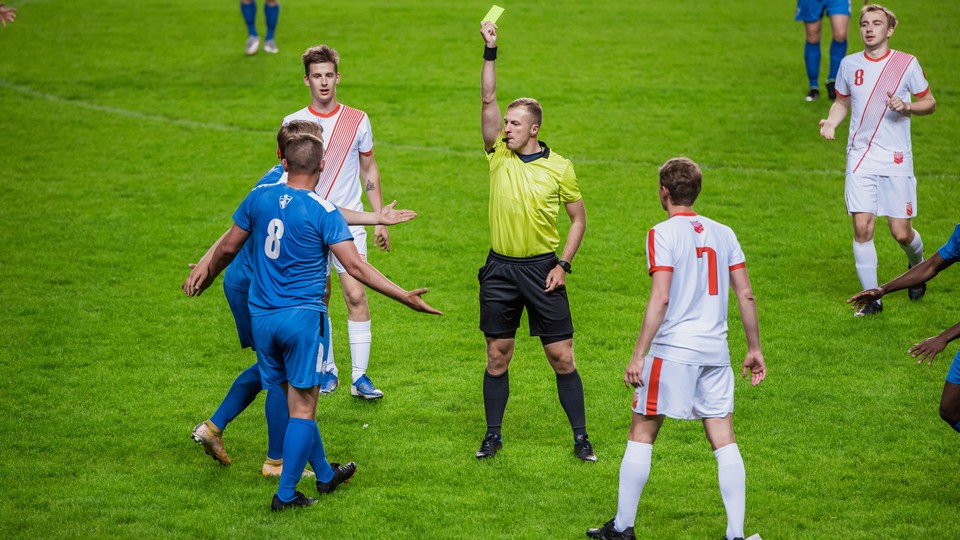 Referee pulls yellow card on soccer player